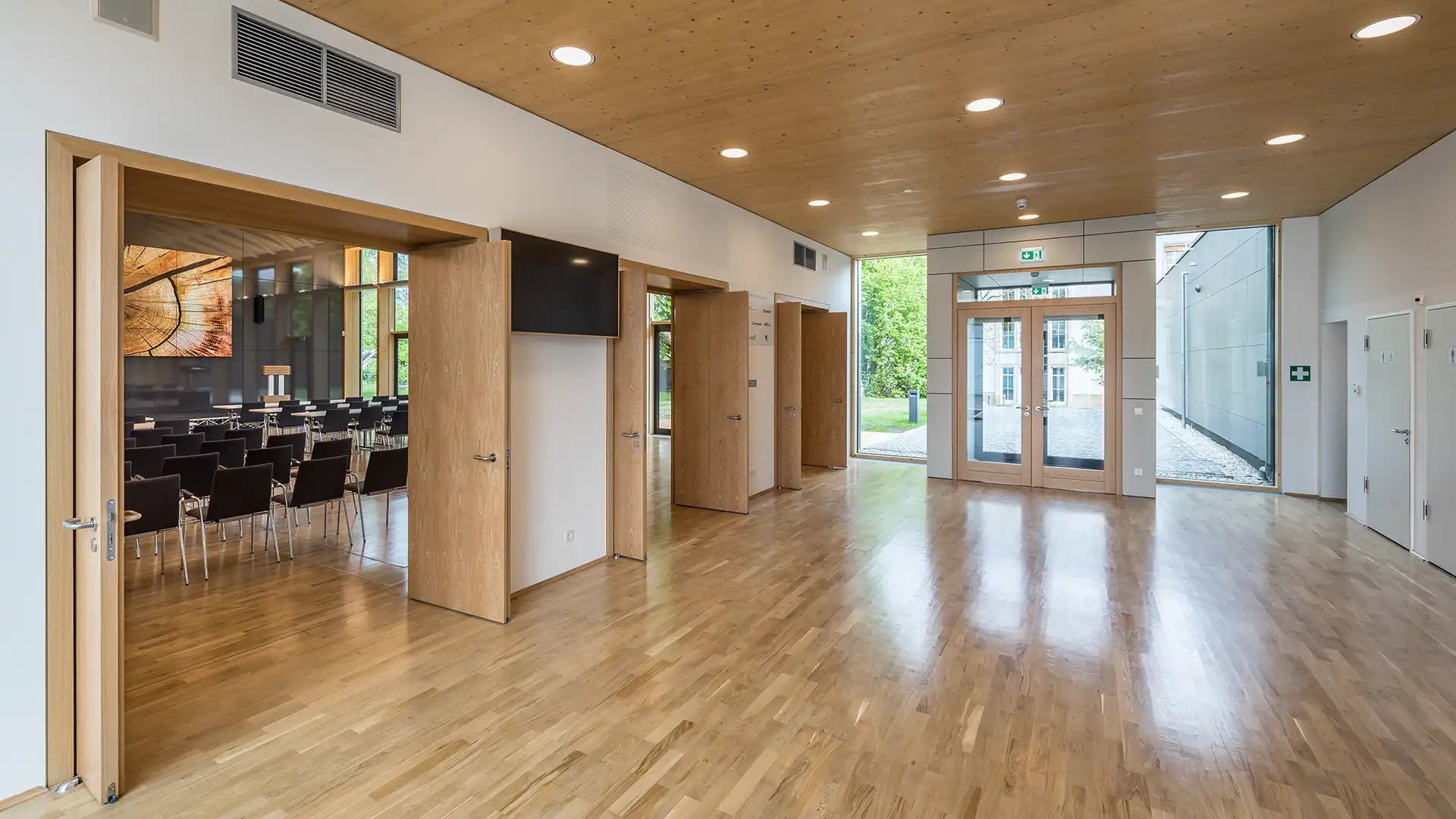 Helles Foyer mit Holzboden und Holzdecke. Blick in Richtung des Konferenzsaales