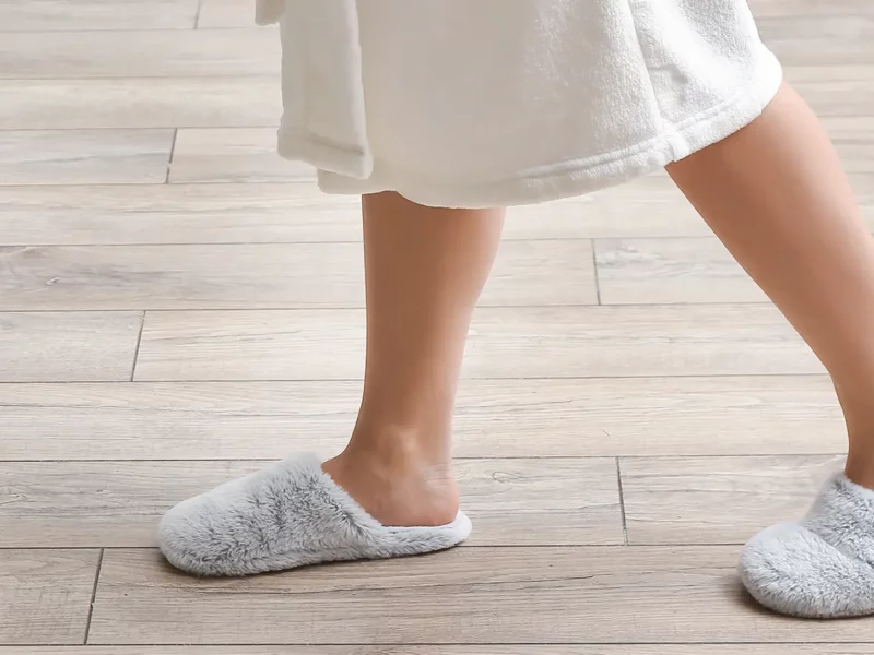 Person wearing slippers on light wooden floor indoors
