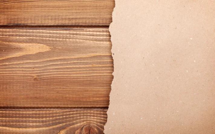 Holzoberfläche mit Papierkante als Symbol für Dokumentation und Forschung