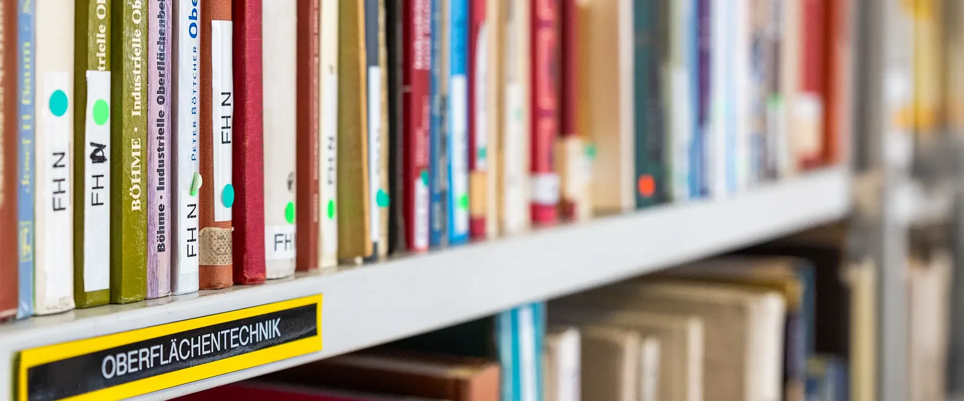 Teilansicht einer Institutsbibliothek im Bereich Oberflächentechnik: im Vordergrund Bücher oder Magazine mit weicherem Verlauf in den Hintergrund