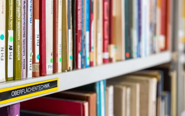 Teilansicht einer Institutsbibliothek im Bereich Oberflächentechnik: im Vordergrund Bücher oder Magazine mit weicherem Verlauf in den Hintergrund