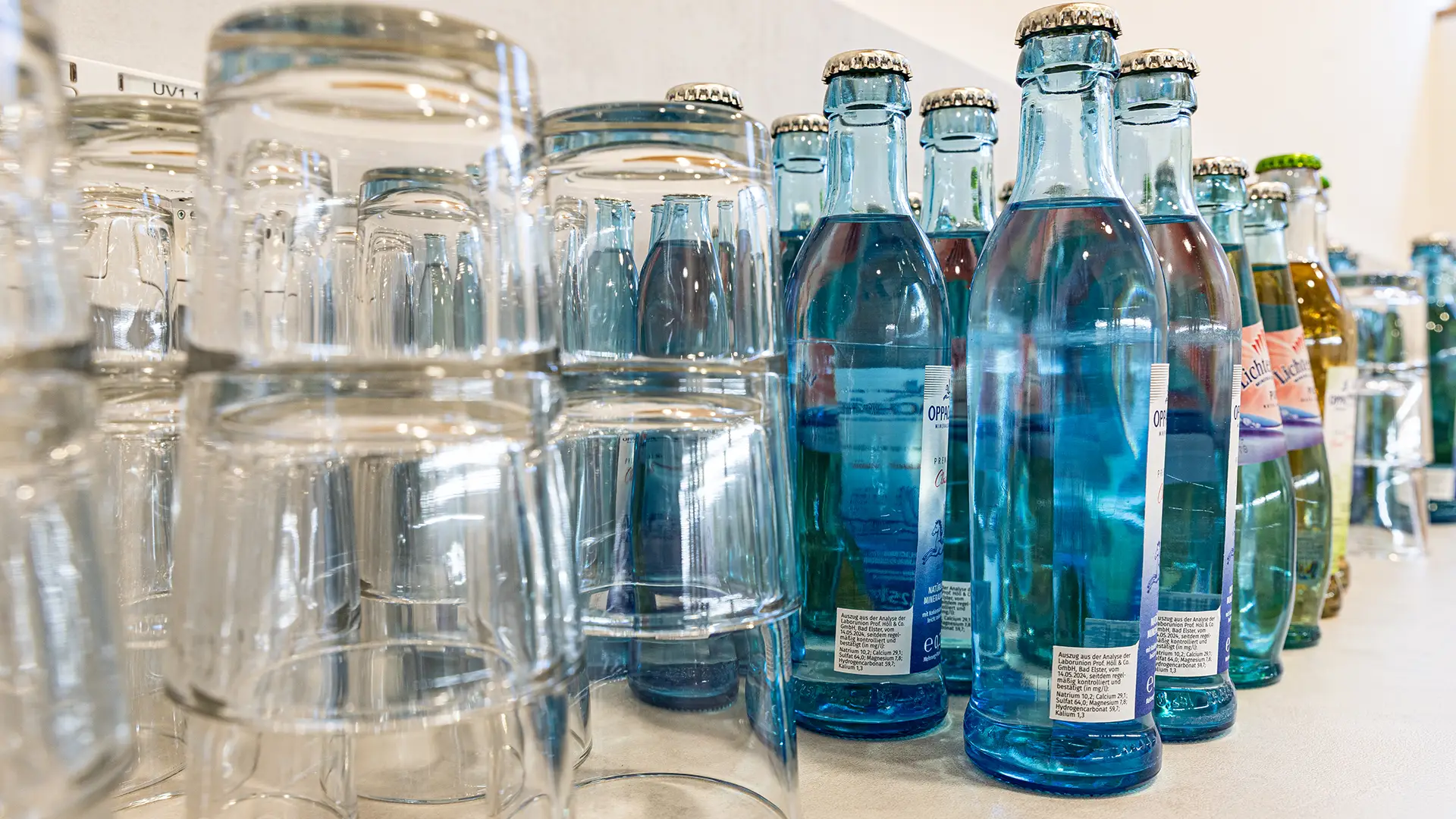 Mineralwasserflaschen und Trinkgläser auf Getränketisch bei einer Veranstaltung