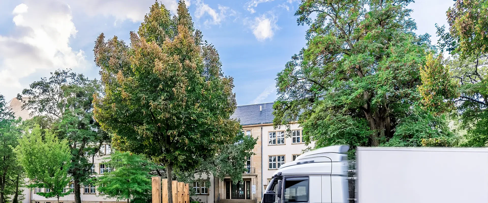 Institutsgebäude mit Bäumen und Lkw vor dem Eingang