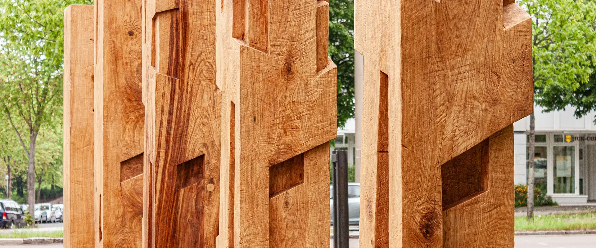 Massive Holzskulpturen mit geometrischen Fräsungen im Außenbereich