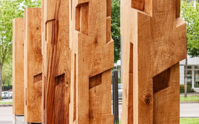 Massive Holzskulpturen mit geometrischen Fräsungen im Außenbereich