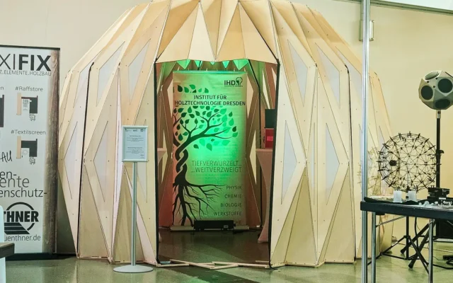 Messestand des Instituts für Holztechnologie Dresden mit kuppelförmiger Holzstruktur und beleuchtetem IHD-Banner auf einer Fachmesse