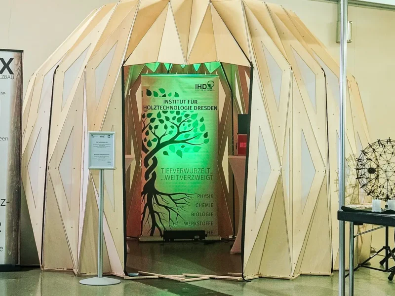 Messestand des Instituts für Holztechnologie Dresden mit kuppelförmiger Holzstruktur und beleuchtetem IHD-Banner auf einer Fachmesse